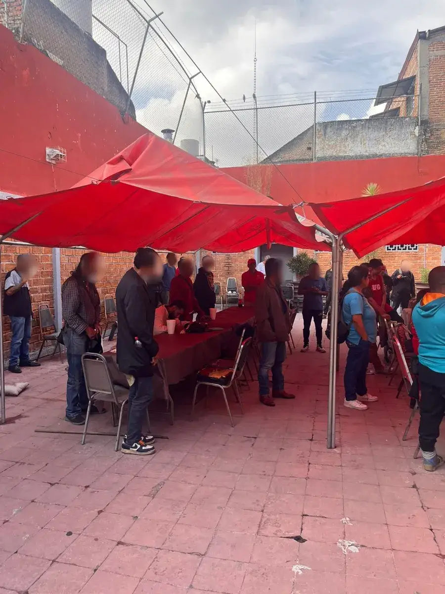 Voluntarios sirviendo el desayuno bajo las lonas del patio
